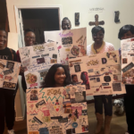 Group of women smiling and posing for photo and holding up posters