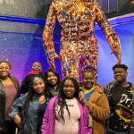 Group of people posing for a photo in front of a sculpture.