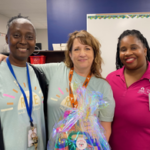 Three women smiling and posing for a photo in a classroom.