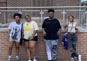 Four students pose in front of a brick wall.